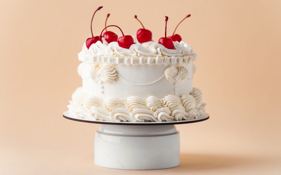 Gâteau vintage à la crème blanche décoré de cerises, illustrant la tendance événementielle 2025 en gâteaux.