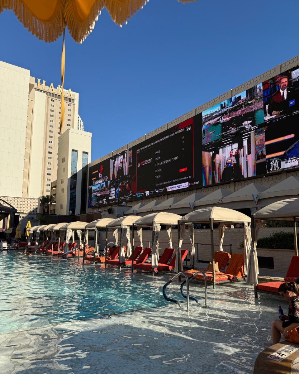 Vue de la piscine du Sahara Hotel à Las Vegas, bordée de cabanas et d’écrans géants diffusant des matchs. L’image reflète la détente et la célébration qui suivent un mariage à Vegas, entre farniente et ambiance festive.